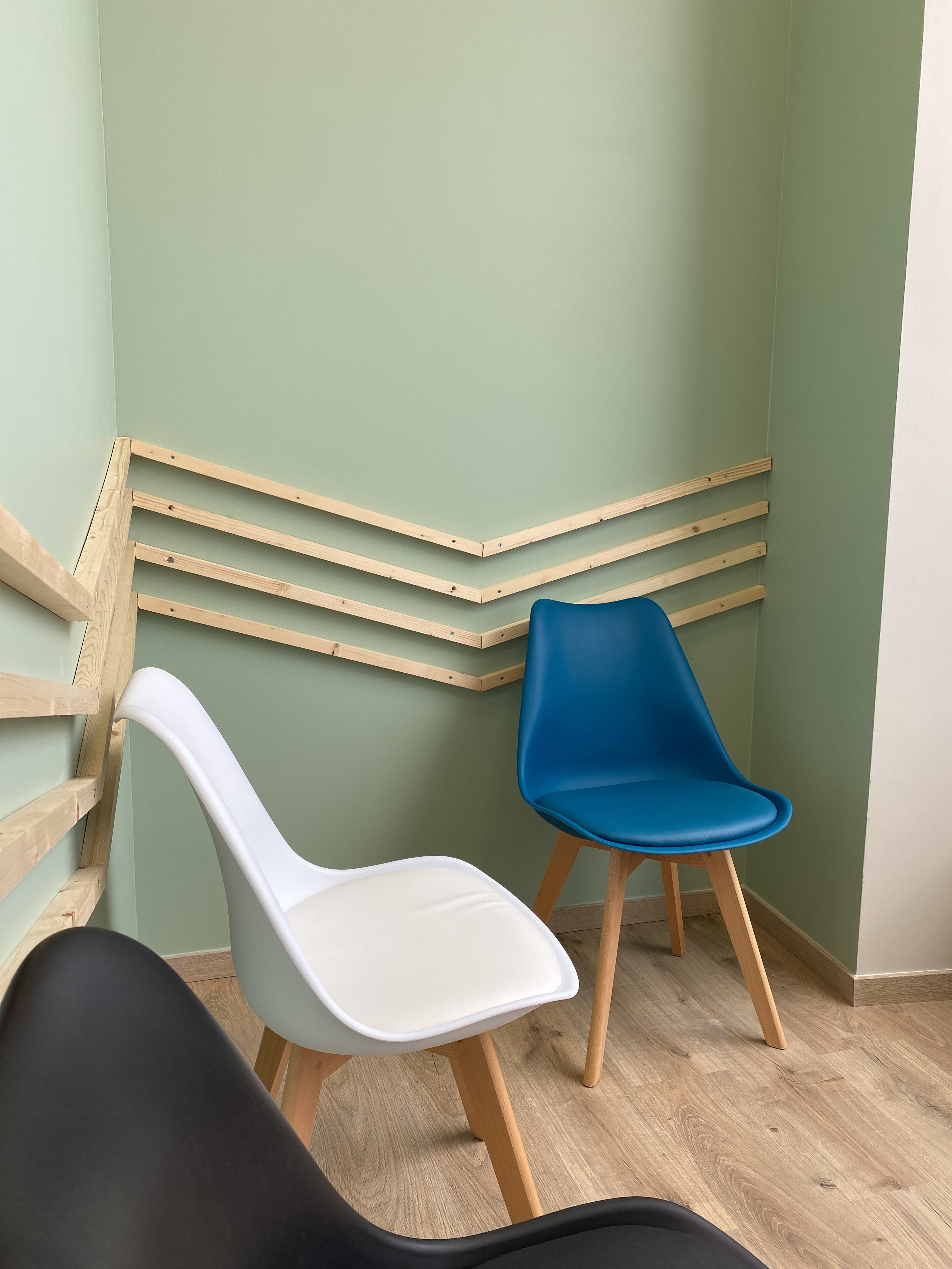 salle d'attente avec des chaises de couleurs et des tasseaux de bois sur le mur