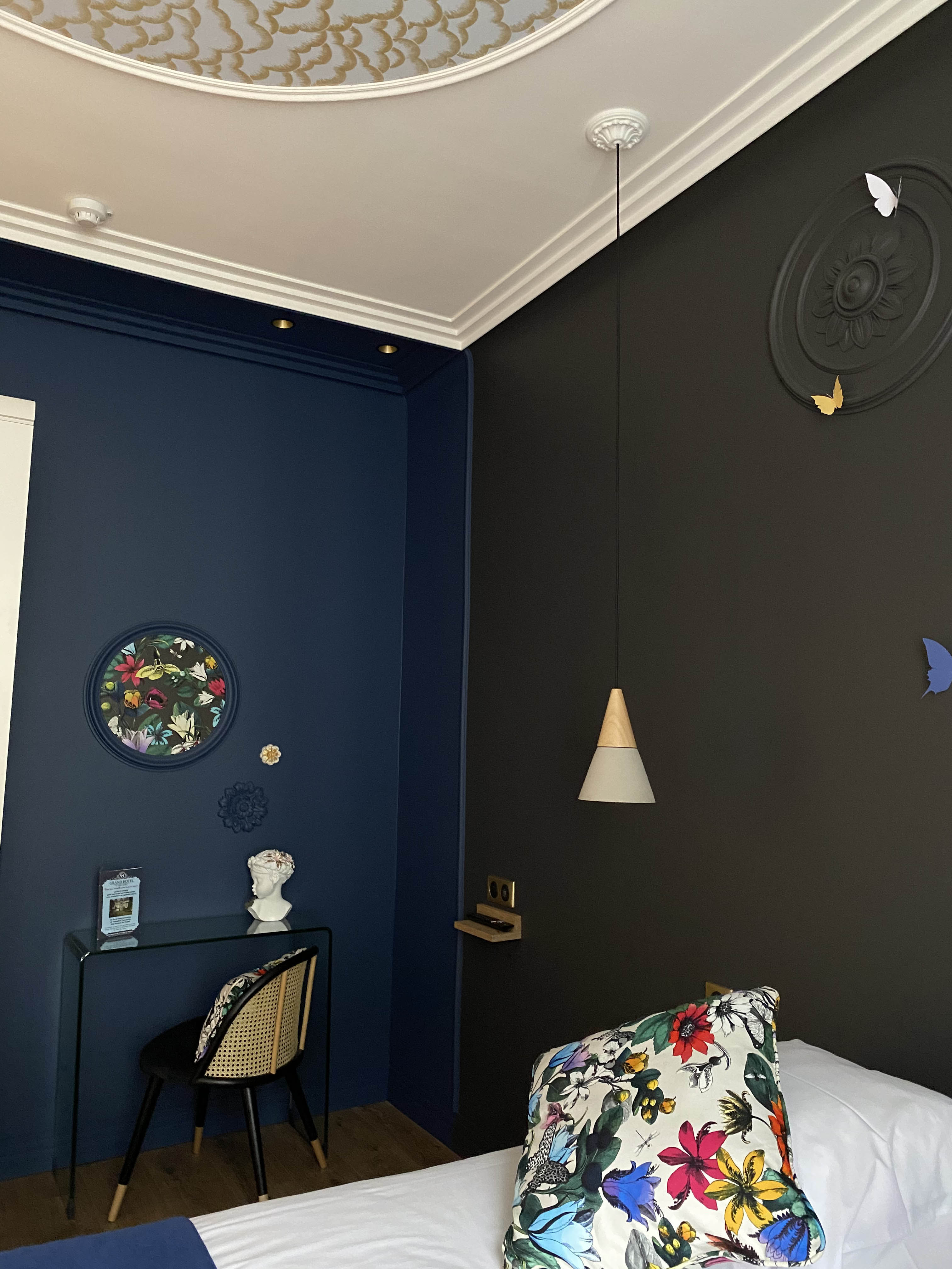 2 murs de couleurs noir pour l'un et bleu foncé pour l'autre avec un luminaire suspendu