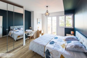 vue d'ensemble d'une chambre avec un lit à gauche une baie vitrée en fond à gauche et un espace à bureau