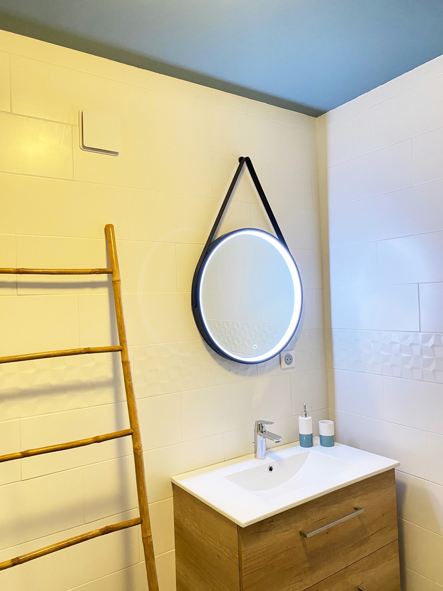 Photo d'une salle de bain, vue sur le lavabo et le miroir éclairé